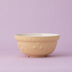 Yellow ceramic bowl with floral patterns on a light purple background