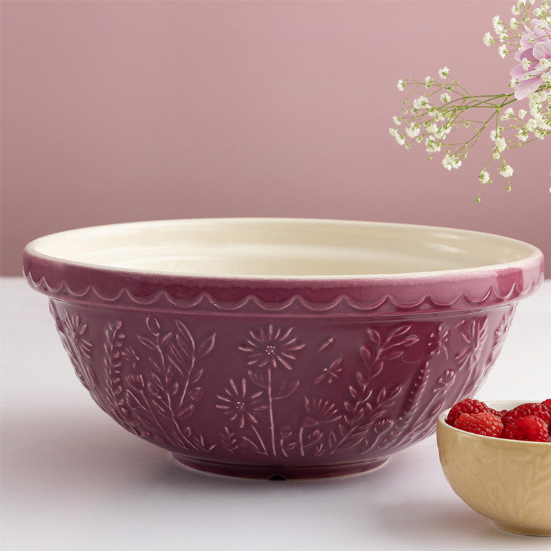 Pink ceramic bowl with floral patterns on a white surface with a pink background