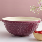 Pink ceramic bowl with floral patterns on a white surface with a pink background