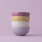 Stack of four ceramic bowls with floral patterns on a light purple background