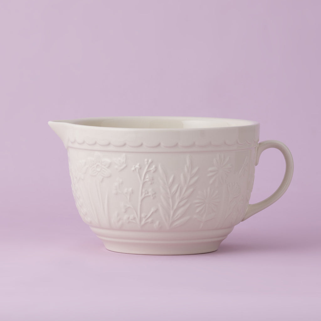 White ceramic mixing bowl with floral patterns on a light purple background