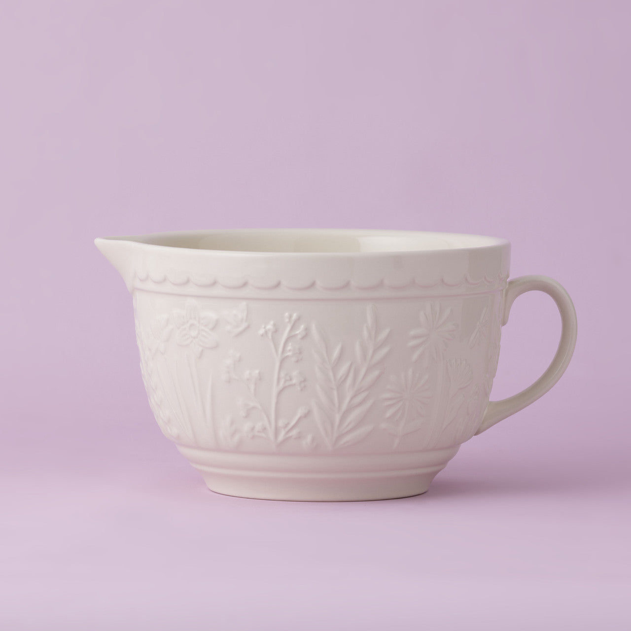 White ceramic mixing bowl with floral patterns on a light purple background