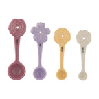 Set of four floral-themed measuring spoons in pink, purple, yellow, and beige on a white background.