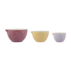 Three ceramic bowls in pink, yellow, and purple with floral patterns on a white background.