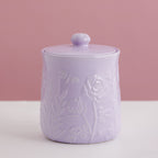 Lavender ceramic jar with floral embossing on a pink background