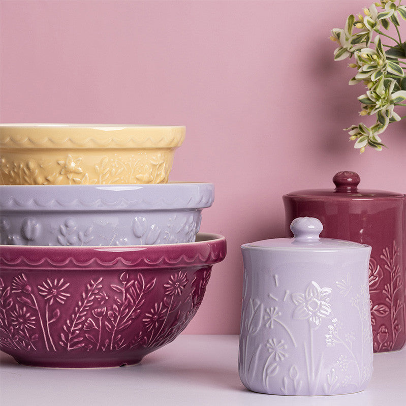 Set of ceramic bowls and canisters with floral patterns on a pink background
