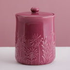 Pink ceramic jar with floral embossing on a pink background
