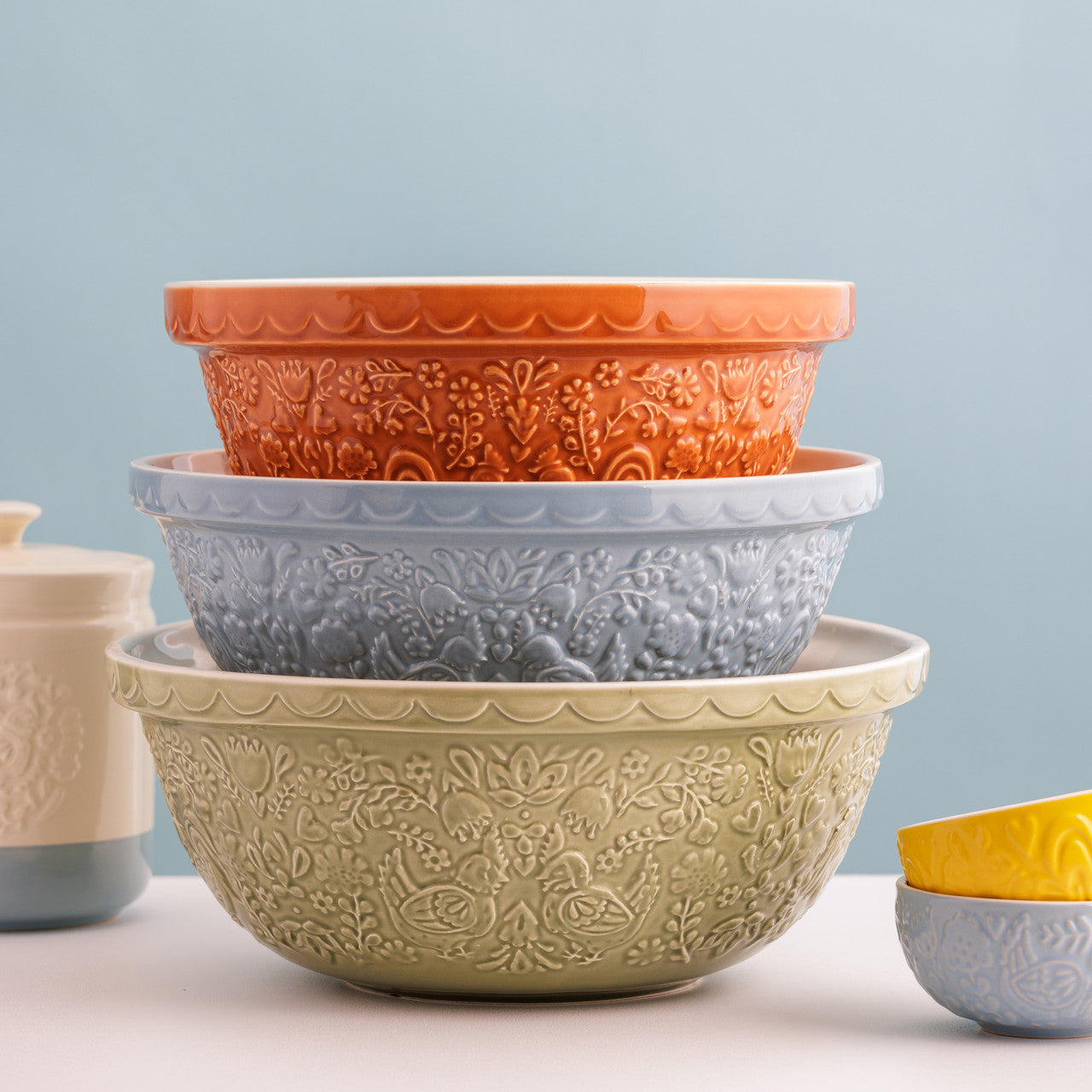 Set of embossed ceramic bowls in various colors on a light blue background