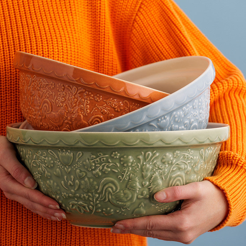 Three decorative bowls stacked, held by a person wearing an orange sweater.