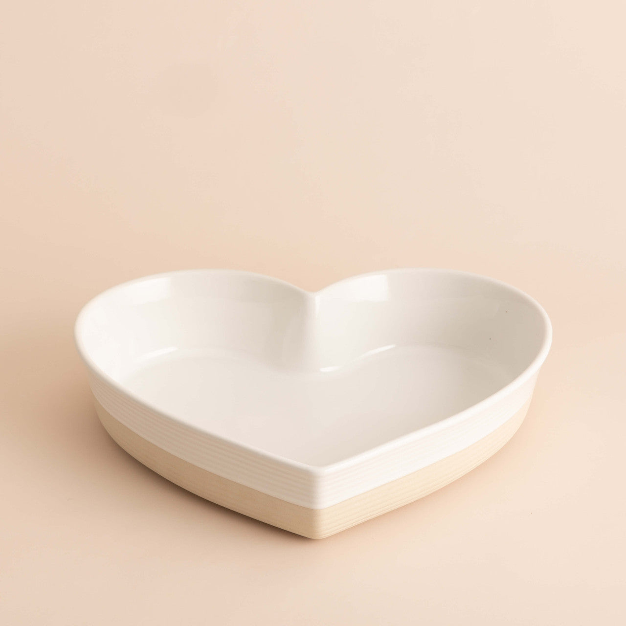 Heart-shaped white ceramic bowl on a beige background