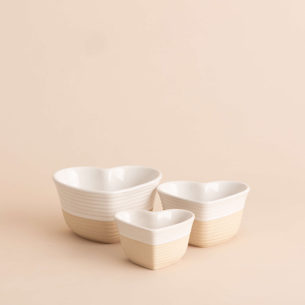 Three white ceramic bowls of different sizes on a beige background
