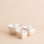 Three white ceramic bowls of different sizes on a beige background