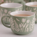 Green mugs with floral patterns on a light background
