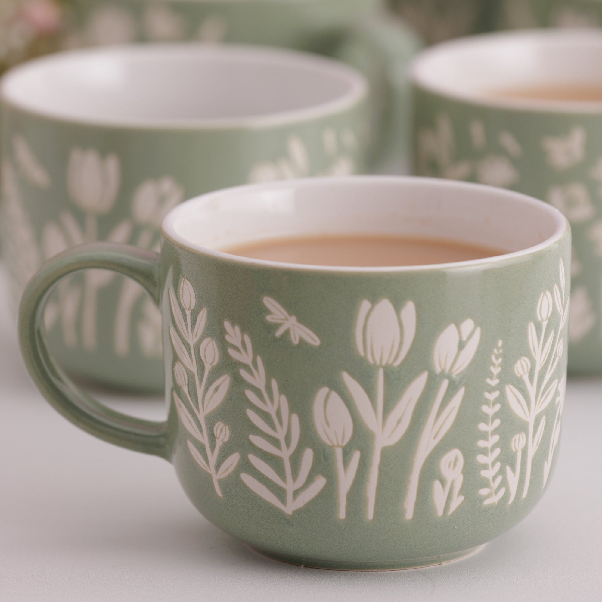 Green mugs with floral patterns on a light background
