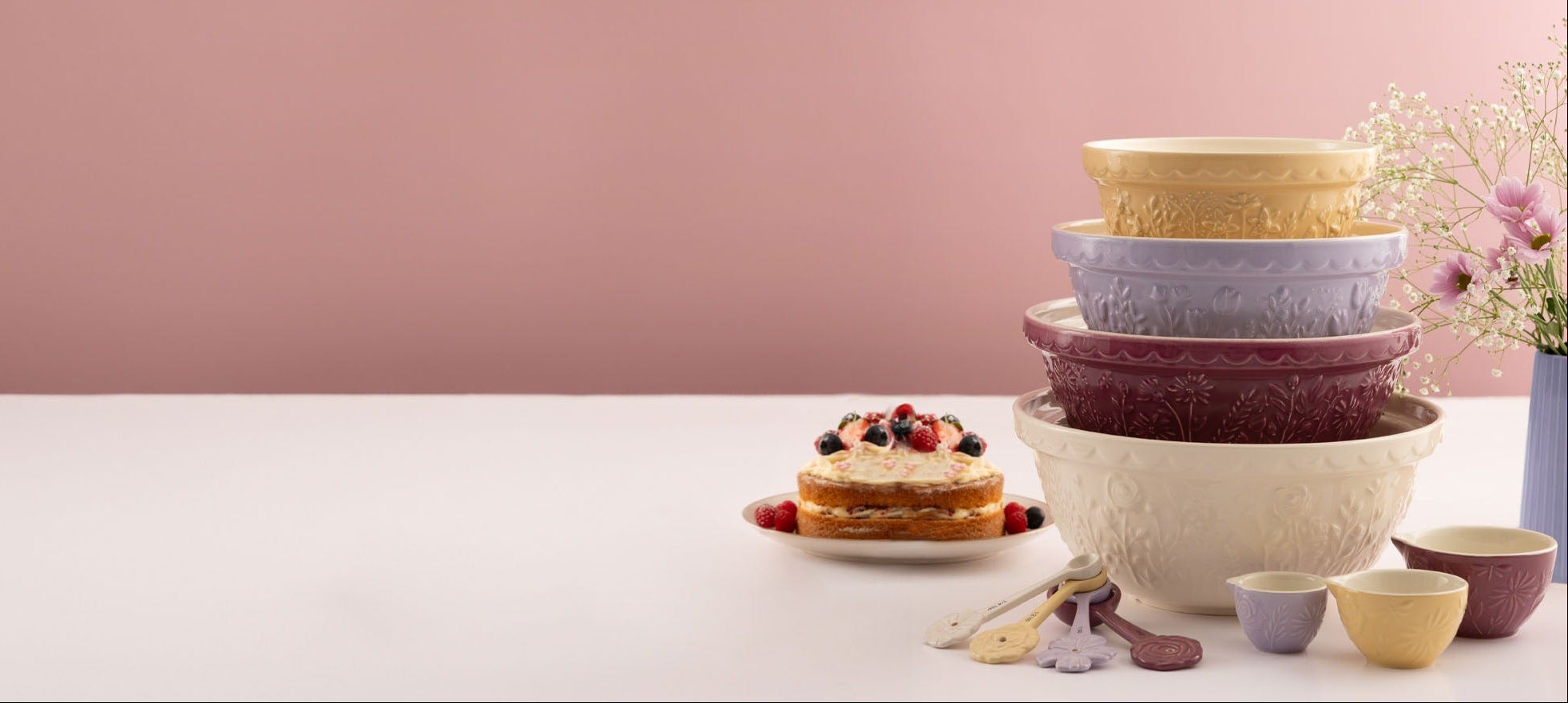 Stack of colorful ceramic bowls on a white surface with a pink background